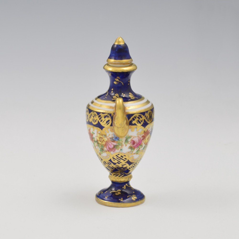An Edwardian miniature cobalt blue porcelain scent bottle in urn form with twin gilt handles and hand-painted floral panels. View IV