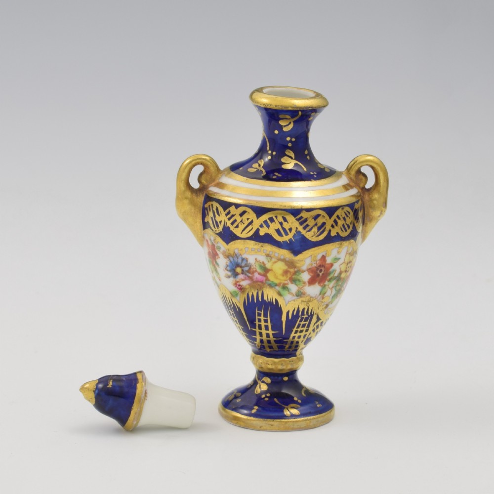 An Edwardian miniature cobalt blue porcelain scent bottle in urn form with twin gilt handles and hand-painted floral panels. View V
