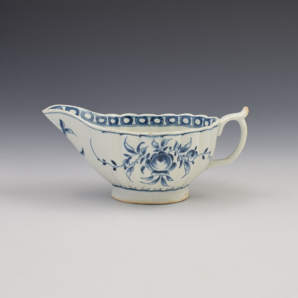 An eighteenth-century First Period Worcester blue and white soft-paste porcelain sauce boat featuring hand-painted rose motifs and a moulded body.