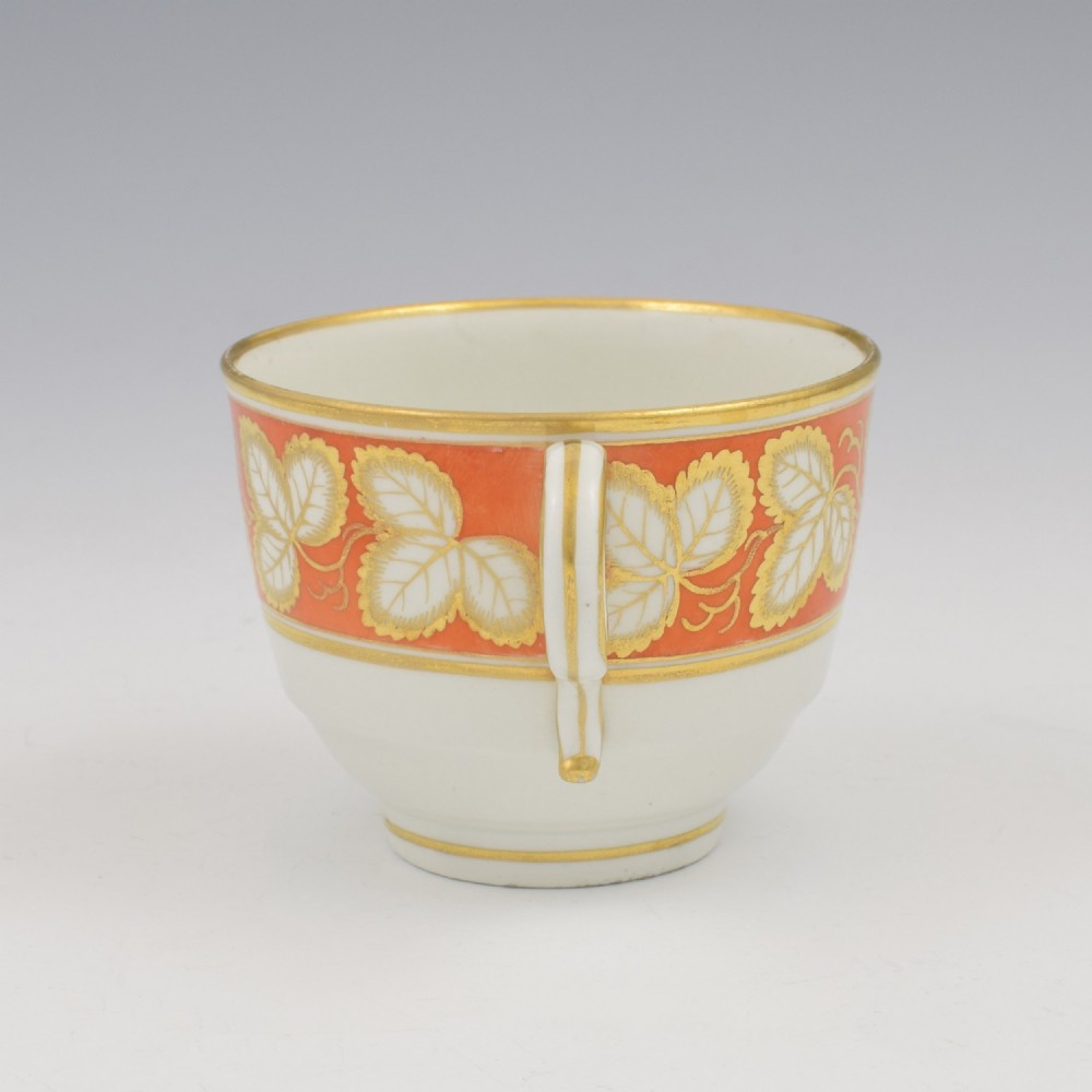 An early 19th-century Worcester porcelain tea cup and saucer featuring an orange border decorated with gilded leaf motifs on a white ground. View VI