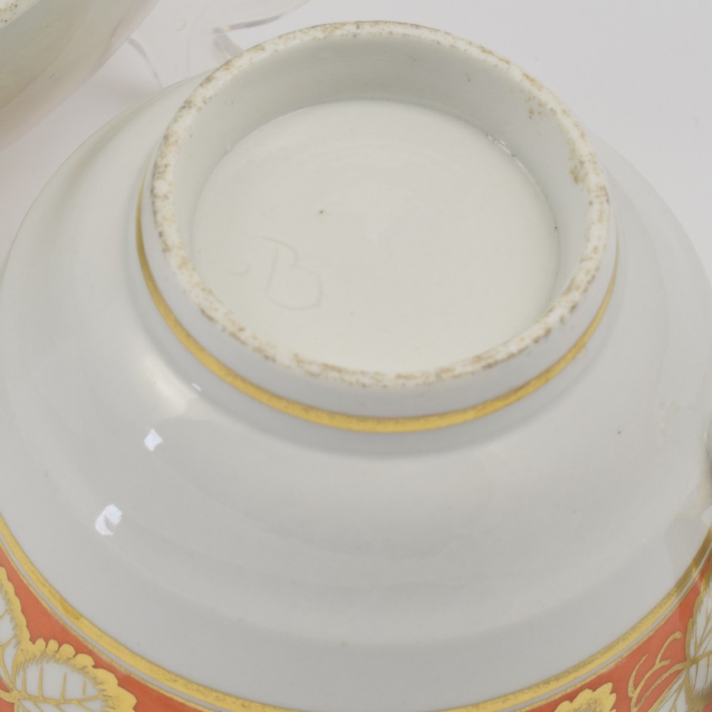 An early 19th-century Worcester porcelain tea cup and saucer featuring an orange border decorated with gilded leaf motifs on a white ground. View VIII