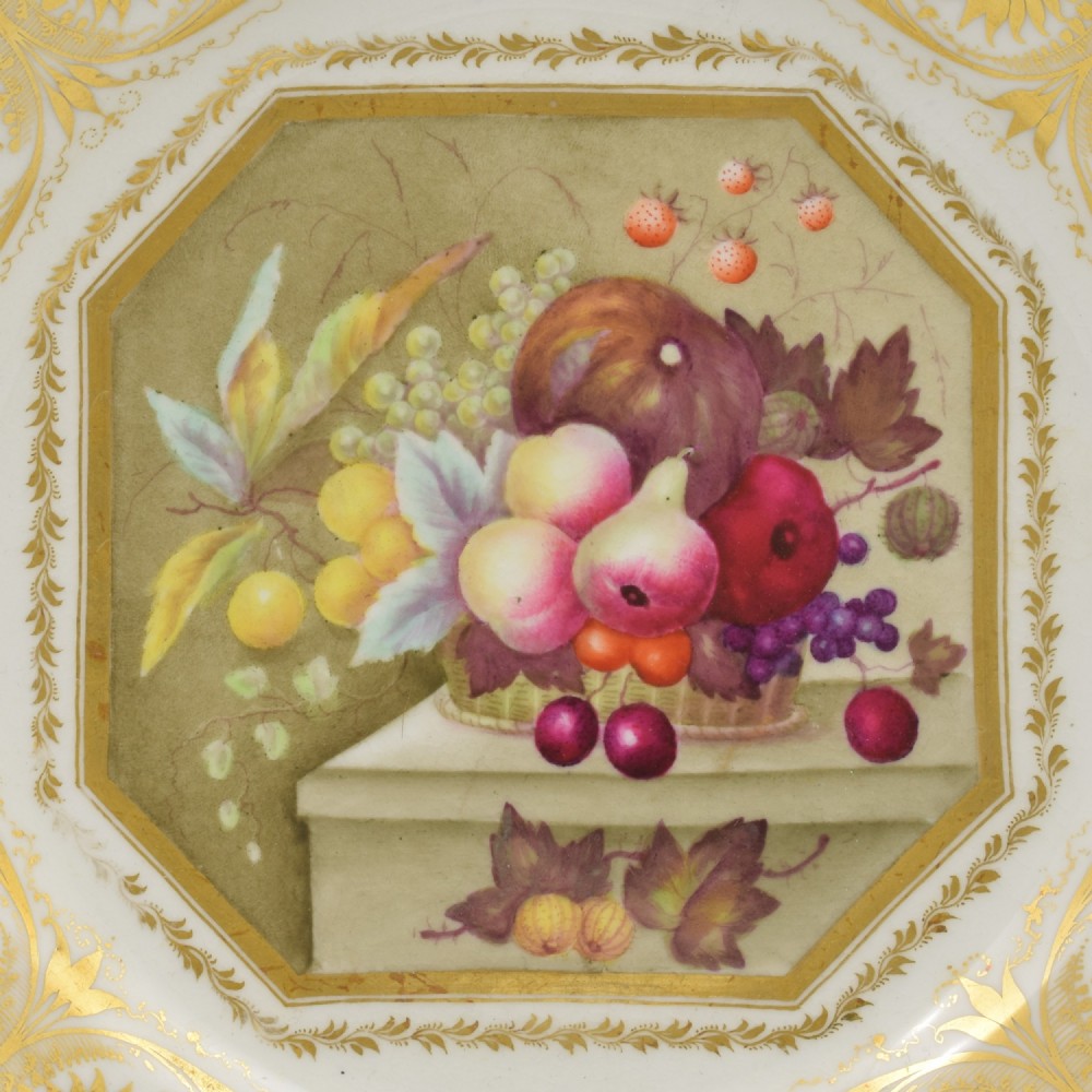 A Regency era Derby porcelain dessert plate featuring a central octagonal panel hand-painted with still-life fruit on a stone ledge, bordered by intricate gold gilding. View II