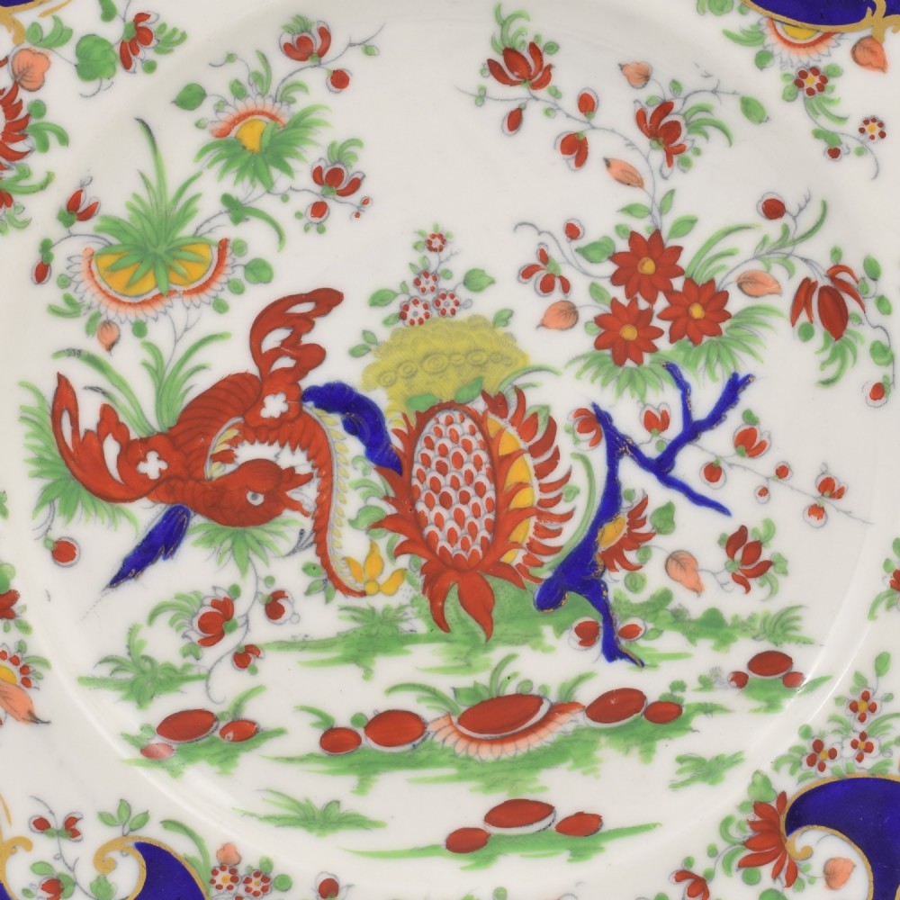 A lobed porcelain dessert plate featuring a rich cobalt blue border with gilded scrollwork and a hand-painted central design of a mythical creature among flowers. View II