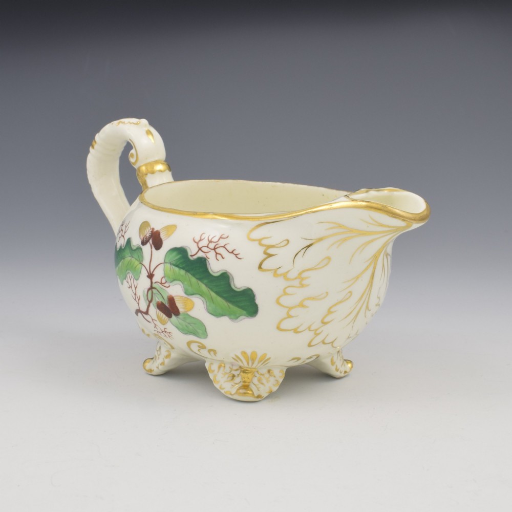 A cream-coloured Regency porcelain jug featuring hand-painted green oak leaves, brown acorns, moulded feet, and gilded trim. View III