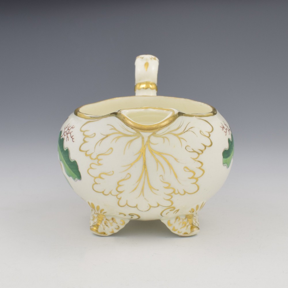 A cream-coloured Regency porcelain jug featuring hand-painted green oak leaves, brown acorns, moulded feet, and gilded trim. View IV