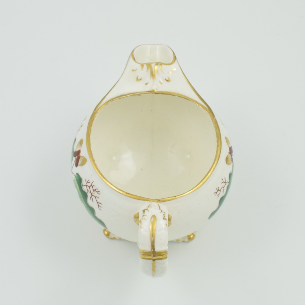 A cream-coloured Regency porcelain jug featuring hand-painted green oak leaves, brown acorns, moulded feet, and gilded trim. View XII