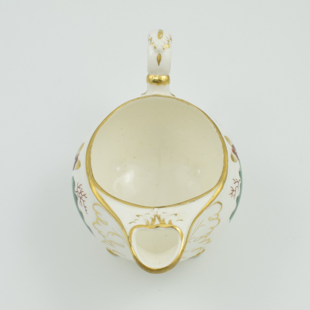 A cream-coloured Regency porcelain jug featuring hand-painted green oak leaves, brown acorns, moulded feet, and gilded trim. View XIII