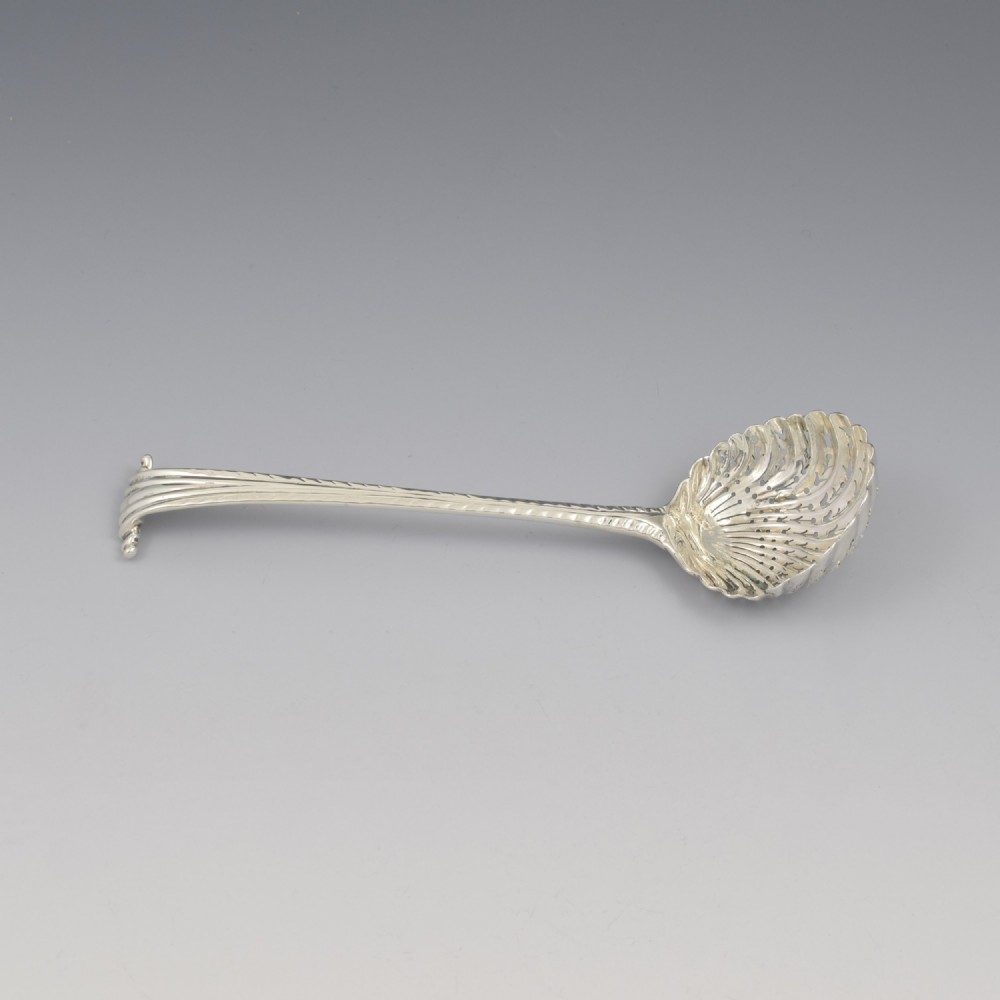 An 18th-century sterling silver sifter spoon featuring an Onslow scroll terminal, feather-edge shaft, and a pierced shell bowl. View V