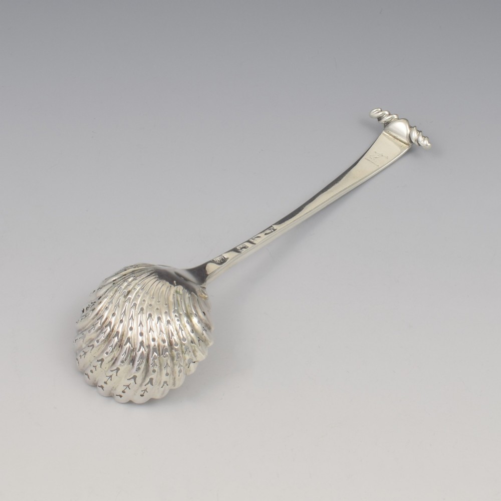 An 18th-century sterling silver sifter spoon featuring an Onslow scroll terminal, feather-edge shaft, and a pierced shell bowl. View VIII