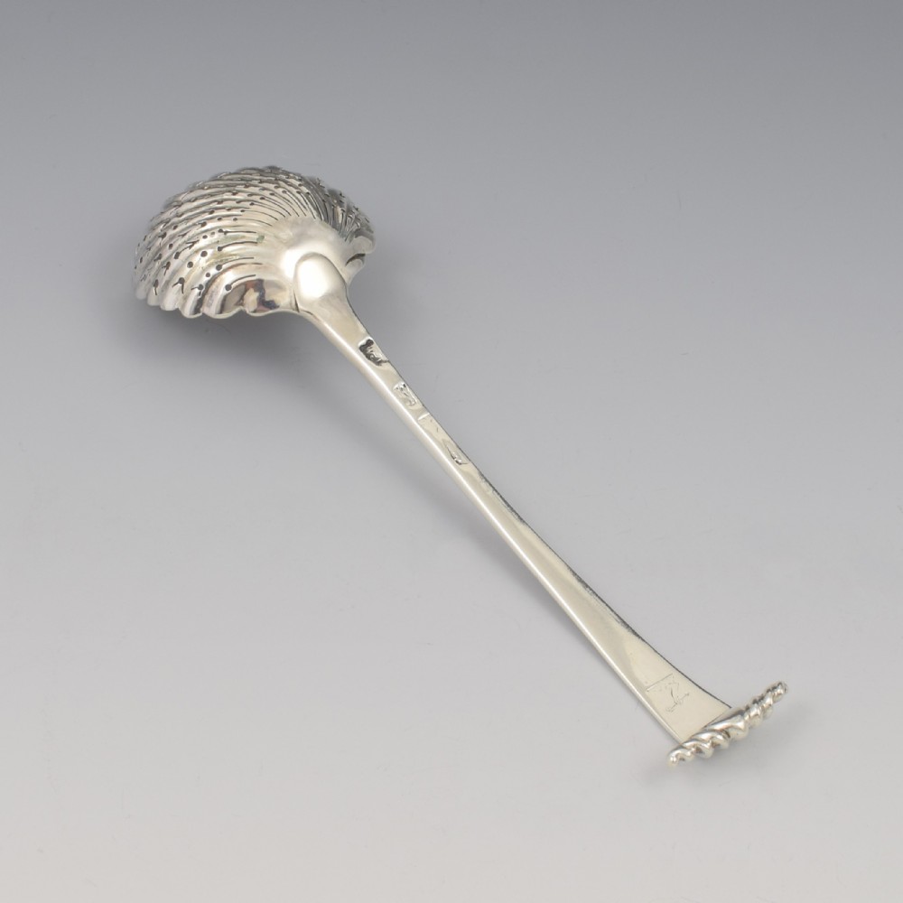 An 18th-century sterling silver sifter spoon featuring an Onslow scroll terminal, feather-edge shaft, and a pierced shell bowl. View IX