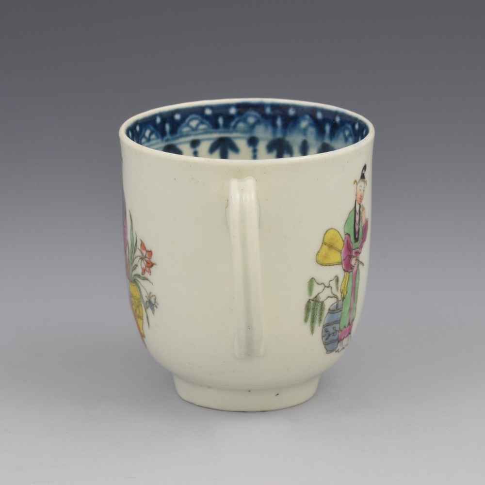 An 18th-century white porcelain coffee cup featuring a hand-painted polychrome figure scene in the Chinoiserie style with a blue patterned inner border. View V