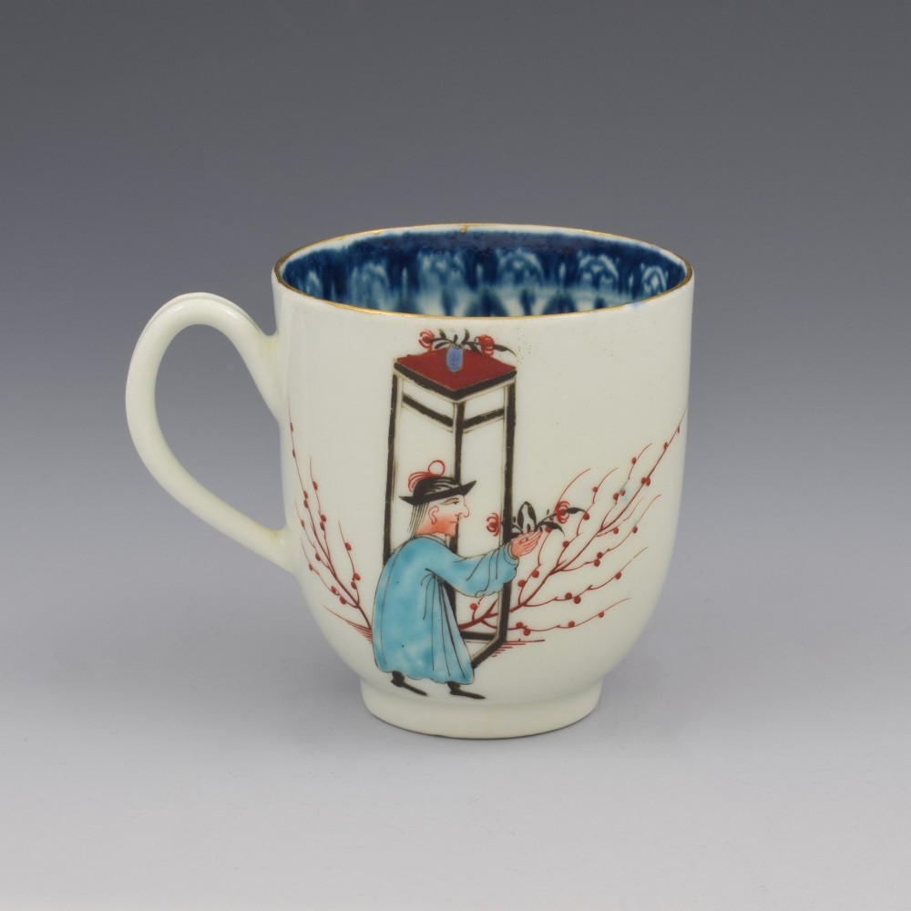 An 18th-century white porcelain coffee cup decorated with hand-painted Chinese figures in red and blue enamel, featuring a single handle and an internal patterned rim.