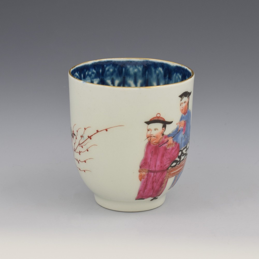 An 18th-century white porcelain coffee cup decorated with hand-painted Chinese figures in red and blue enamel, featuring a single handle and an internal patterned rim. View II