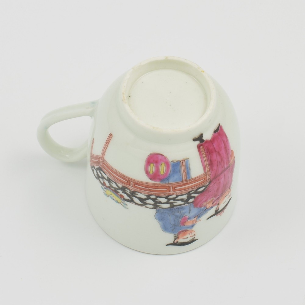 An 18th-century white porcelain coffee cup decorated with hand-painted Chinese figures in red and blue enamel, featuring a single handle and an internal patterned rim. View VII