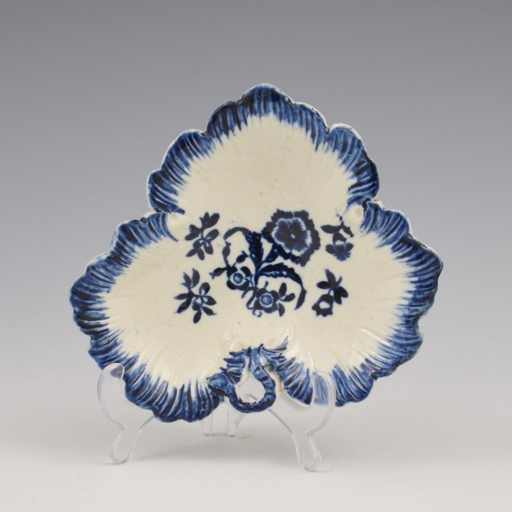 A leaf-shaped Georgian soft-paste porcelain pickle dish decorated with hand-painted underglaze blue floral motifs and a feathered edge.