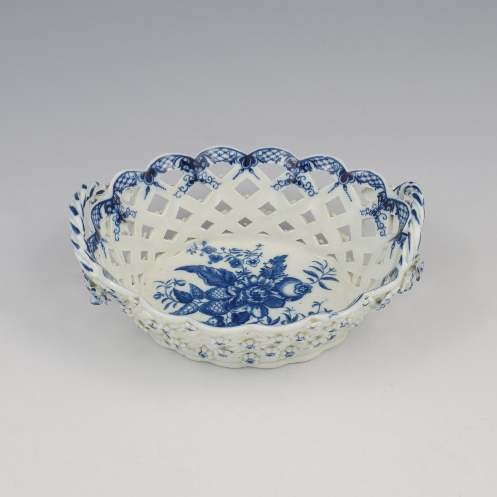 An 18th-century oval blue and white soft-paste porcelain basket with reticulated lattice sides, twisted rope handles, and an underglaze floral pine cone pattern.