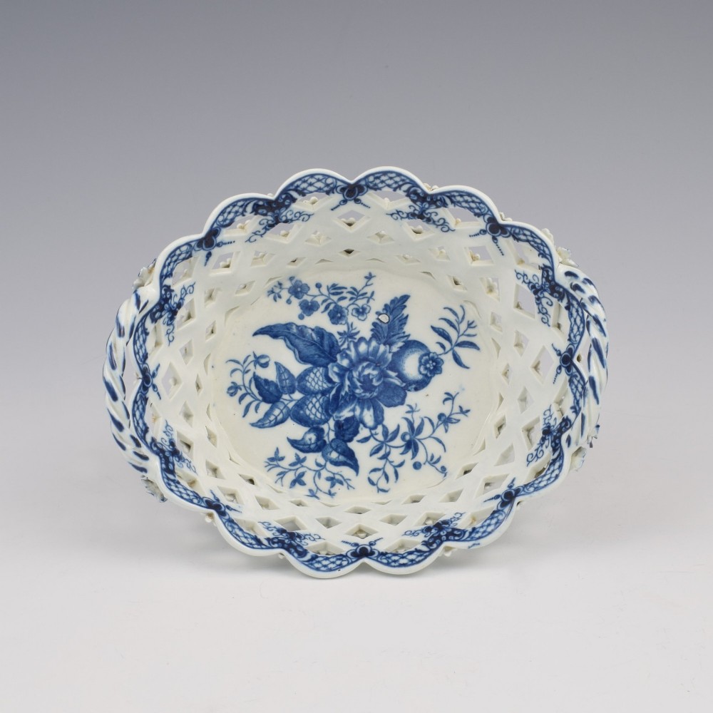 An 18th-century oval blue and white soft-paste porcelain basket with reticulated lattice sides, twisted rope handles, and an underglaze floral pine cone pattern. View II