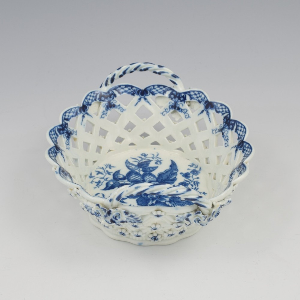 An 18th-century oval blue and white soft-paste porcelain basket with reticulated lattice sides, twisted rope handles, and an underglaze floral pine cone pattern. View V