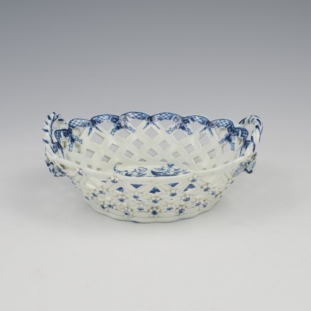An 18th-century oval blue and white soft-paste porcelain basket with reticulated lattice sides, twisted rope handles, and an underglaze floral pine cone pattern. View VI