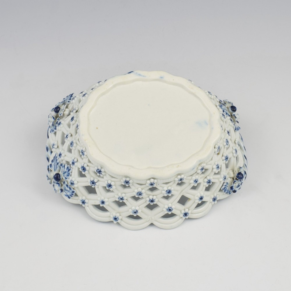 An 18th-century oval blue and white soft-paste porcelain basket with reticulated lattice sides, twisted rope handles, and an underglaze floral pine cone pattern. View VIII