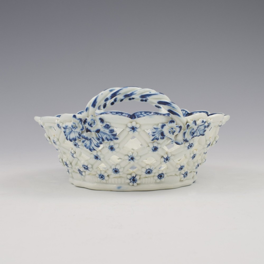 An 18th-century oval blue and white soft-paste porcelain basket with reticulated lattice sides, twisted rope handles, and an underglaze floral pine cone pattern. View X