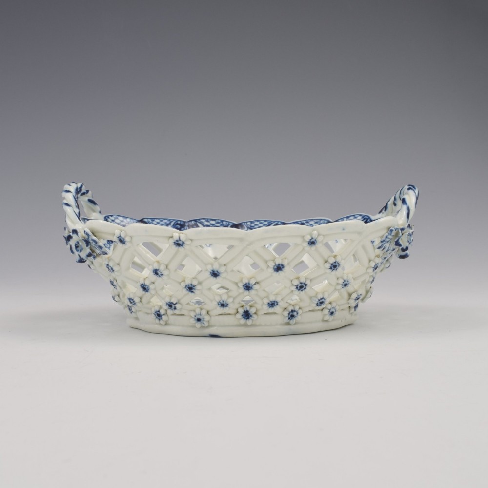 An 18th-century oval blue and white soft-paste porcelain basket with reticulated lattice sides, twisted rope handles, and an underglaze floral pine cone pattern. View XI