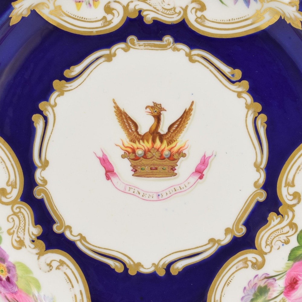 A 19th-century Copeland porcelain plate featuring a cobalt blue border with gilt scrollwork, hand-painted floral cartouches, and a central heraldic crest depicting a phoenix in flames above a coronet. View IV