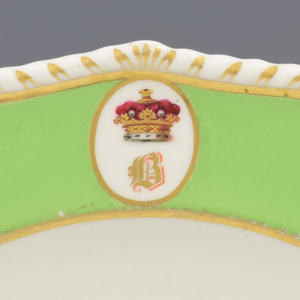 A Regency Bloor Derby porcelain plate featuring an apple green border with a marquess armorial crest, surrounding a central hand-painted illustration of pink Sweet William flowers and butterflies. View III