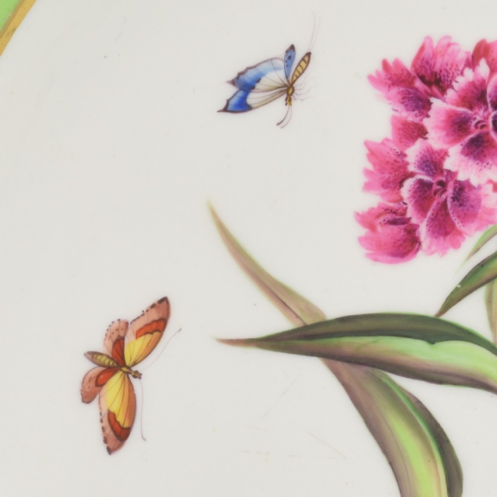 A Regency Bloor Derby porcelain plate featuring an apple green border with a marquess armorial crest, surrounding a central hand-painted illustration of pink Sweet William flowers and butterflies. View V