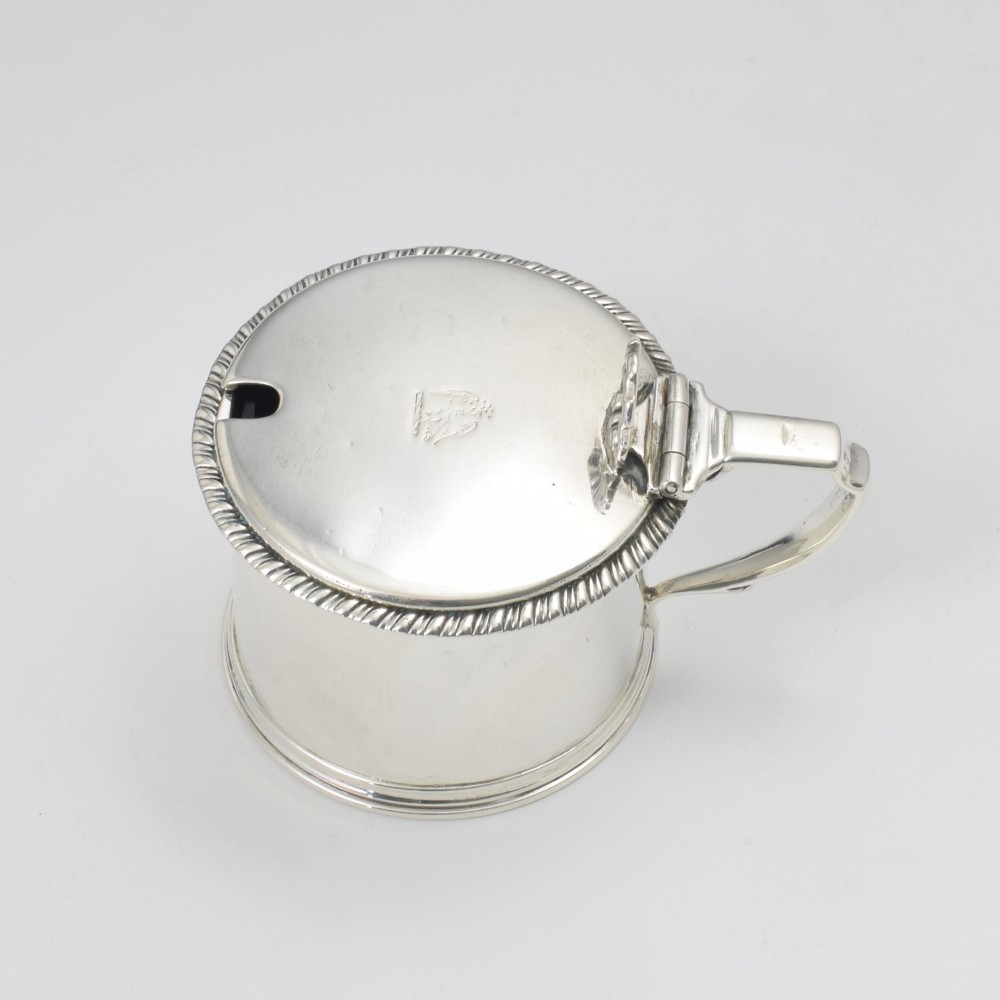 A cylindrical Georgian sterling silver drum mustard pot featuring a hinged lid, shell thumbpiece, and engraved crest. View III
