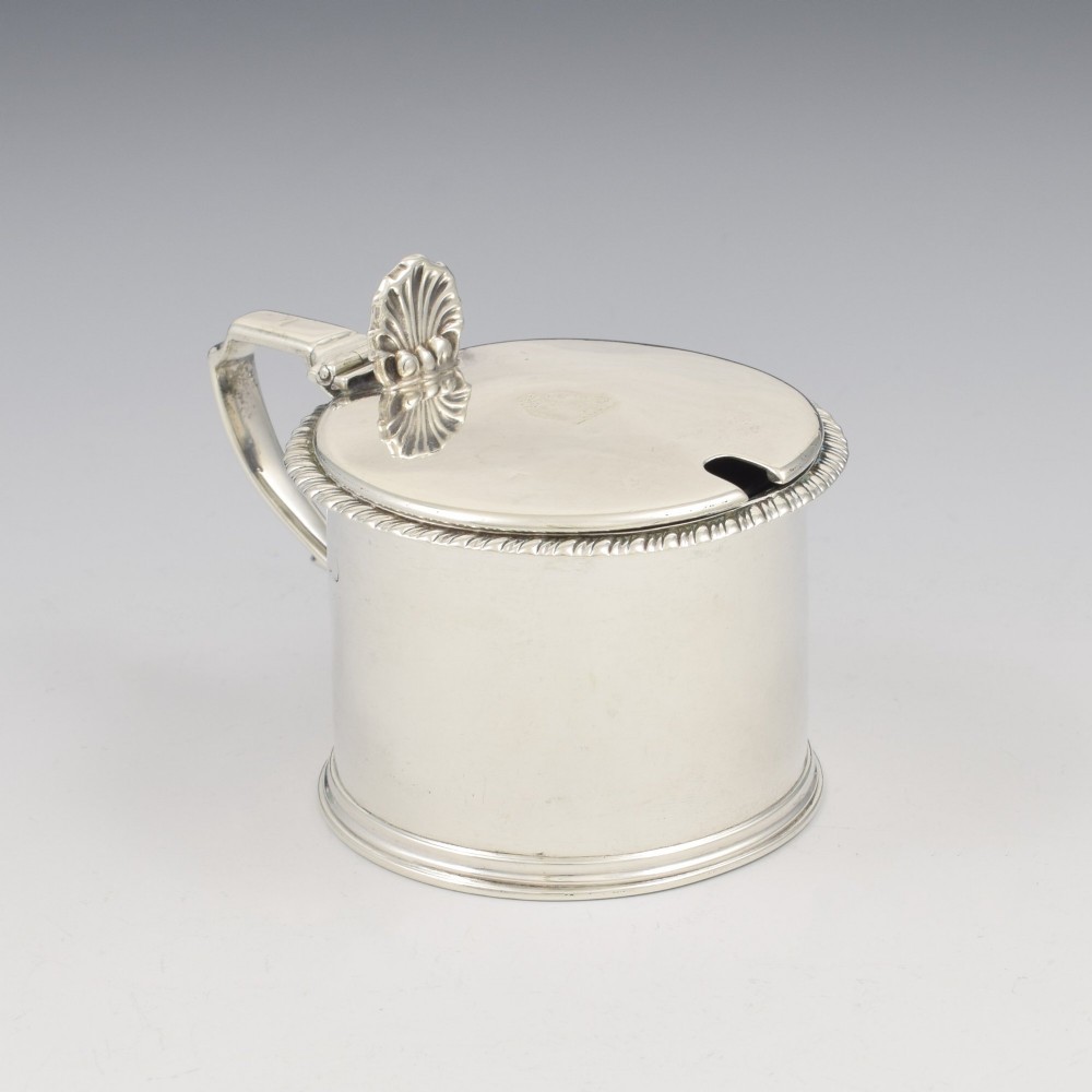 A cylindrical Georgian sterling silver drum mustard pot featuring a hinged lid, shell thumbpiece, and engraved crest. View VII