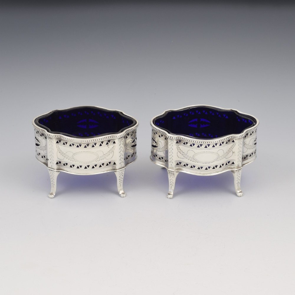 A pair of Victorian silver salt cellars with pierced serpentine frames, four feet, and cobalt blue glass liners. View III