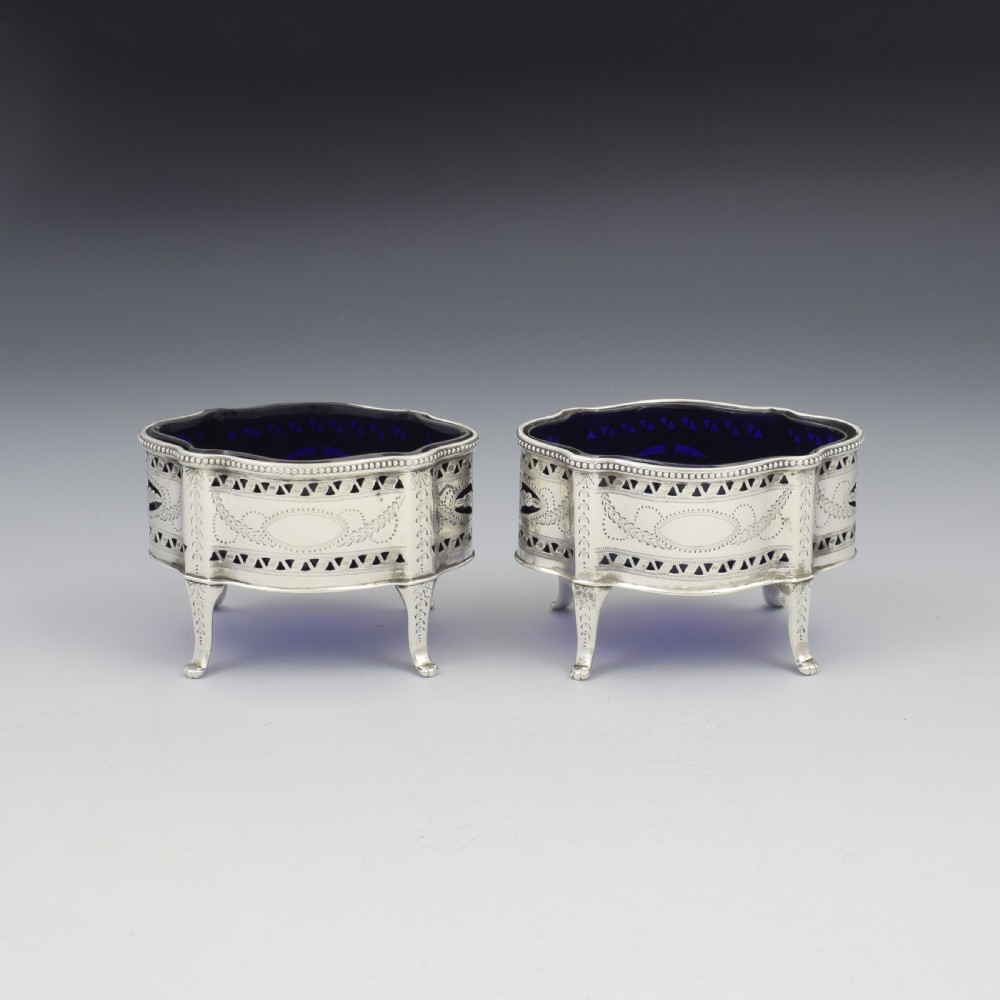 A pair of Victorian silver salt cellars with pierced serpentine frames, four feet, and cobalt blue glass liners. View V