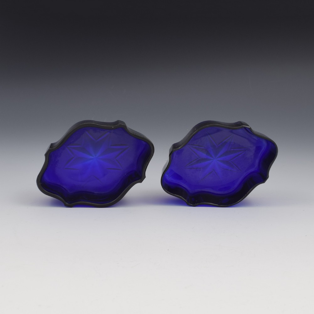 A pair of Victorian silver salt cellars with pierced serpentine frames, four feet, and cobalt blue glass liners. View XIX