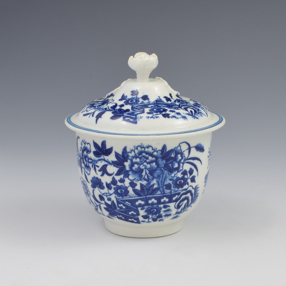 An 18th-century First Period Worcester soft-paste porcelain sucrier featuring an underglaze blue transfer-printed Fence pattern with a domed cover topped by a sculpted floral finial. View II
