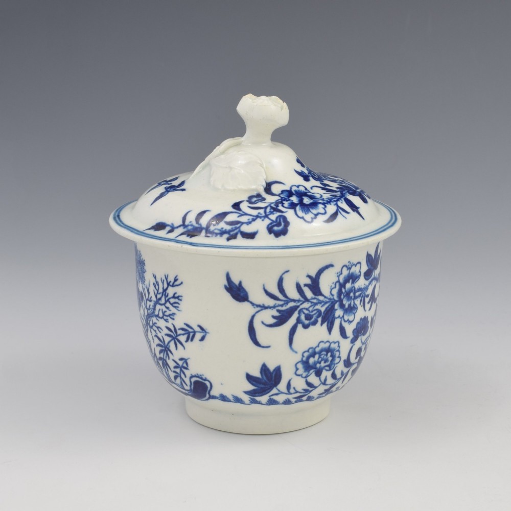 An 18th-century First Period Worcester soft-paste porcelain sucrier featuring an underglaze blue transfer-printed Fence pattern with a domed cover topped by a sculpted floral finial. View V