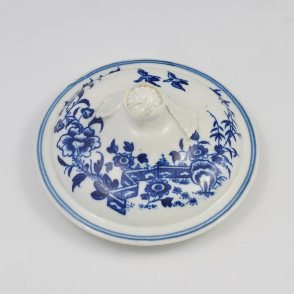 An 18th-century First Period Worcester soft-paste porcelain sucrier featuring an underglaze blue transfer-printed Fence pattern with a domed cover topped by a sculpted floral finial. View VI