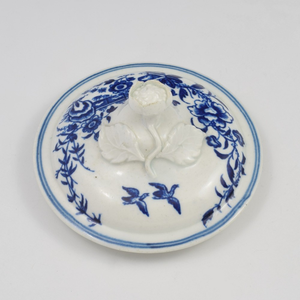An 18th-century First Period Worcester soft-paste porcelain sucrier featuring an underglaze blue transfer-printed Fence pattern with a domed cover topped by a sculpted floral finial. View VII