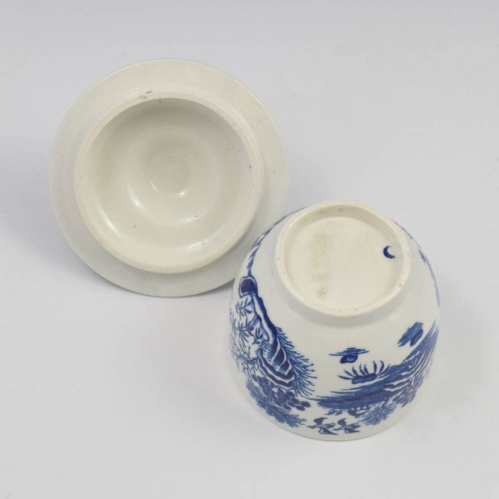 An 18th-century First Period Worcester soft-paste porcelain sucrier featuring an underglaze blue transfer-printed Fence pattern with a domed cover topped by a sculpted floral finial. View VIII