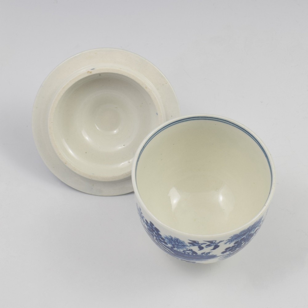 An 18th-century First Period Worcester soft-paste porcelain sucrier featuring an underglaze blue transfer-printed Fence pattern with a domed cover topped by a sculpted floral finial. View IX