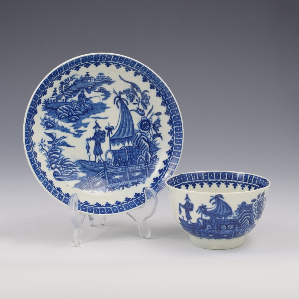 An 18th-century First Period Worcester porcelain tea bowl and saucer set featuring blue underglaze transfer-printed Chinoiserie fisherman patterns.