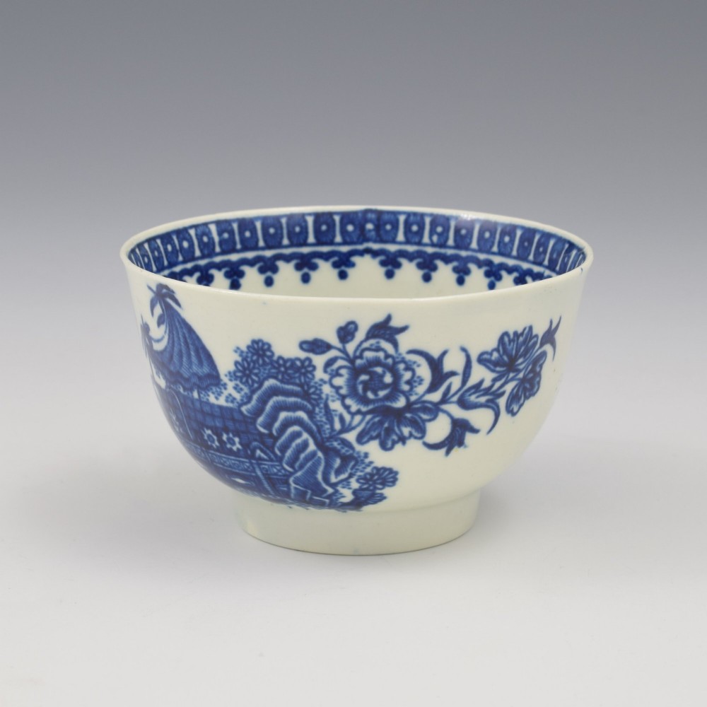 An 18th-century First Period Worcester porcelain tea bowl and saucer set featuring blue underglaze transfer-printed Chinoiserie fisherman patterns. View V