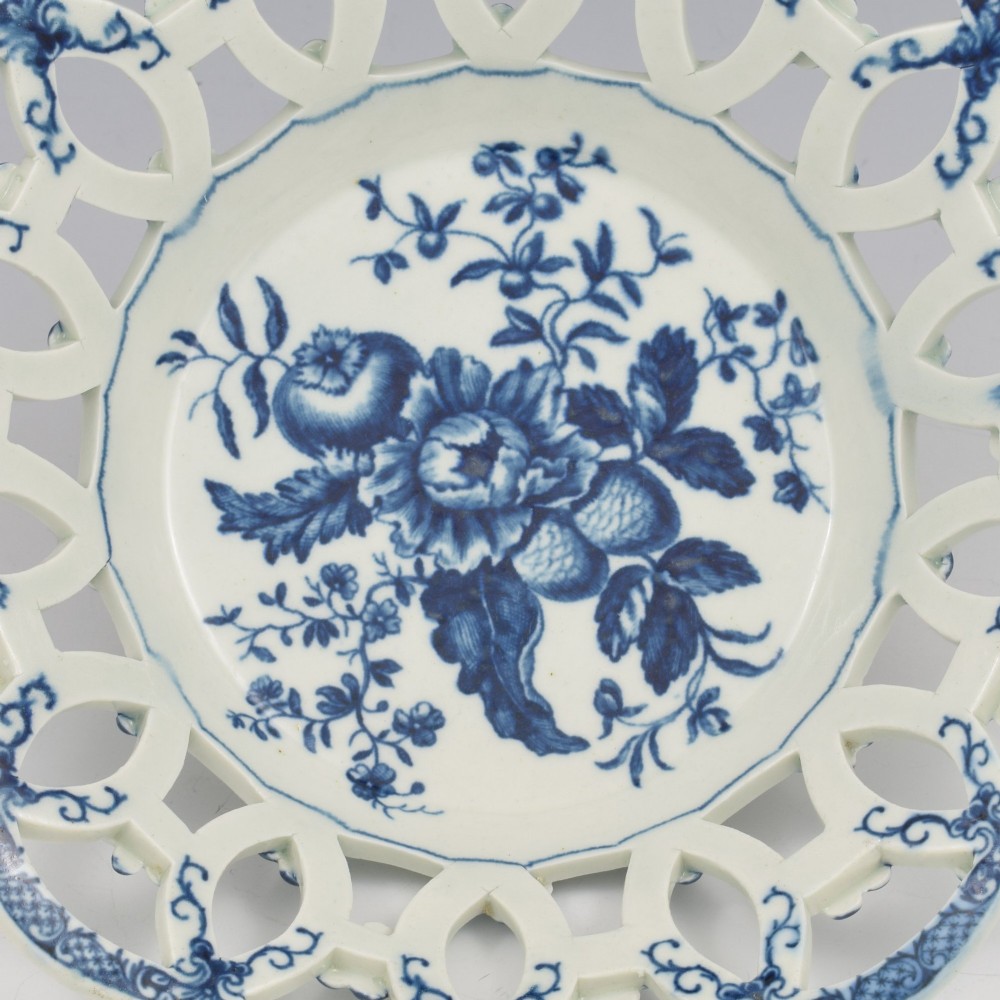 An 18th-century circular blue and white porcelain basket featuring a reticulated lattice rim and a central underglaze transfer print of flowers and pinecones. View II