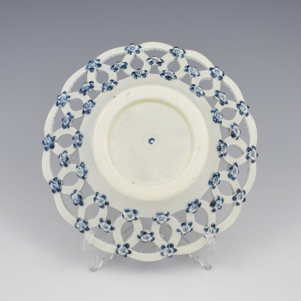 An 18th-century circular blue and white porcelain basket featuring a reticulated lattice rim and a central underglaze transfer print of flowers and pinecones. View IV
