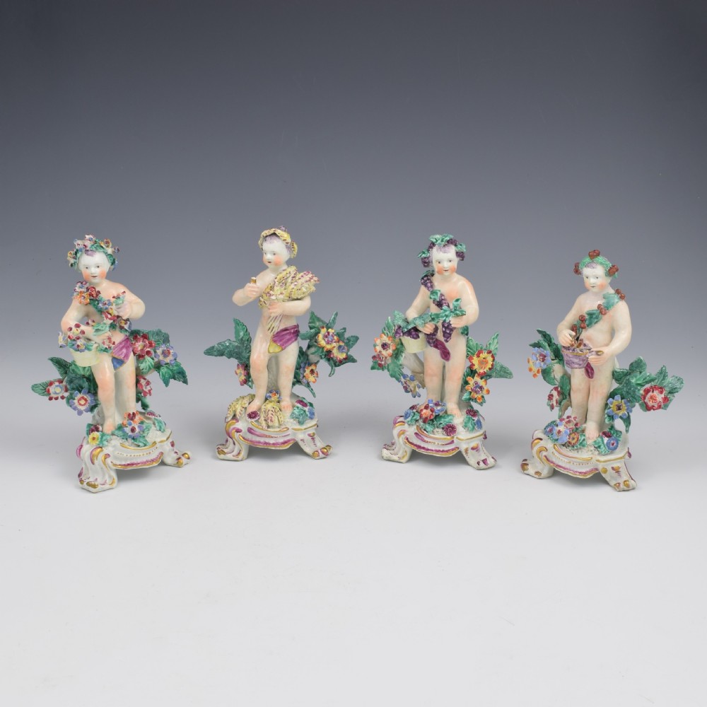 A set of four 18th-century Bow soft-paste porcelain figures representing the seasons, depicting putti on rococo scroll bases with colourful floral bocage.
