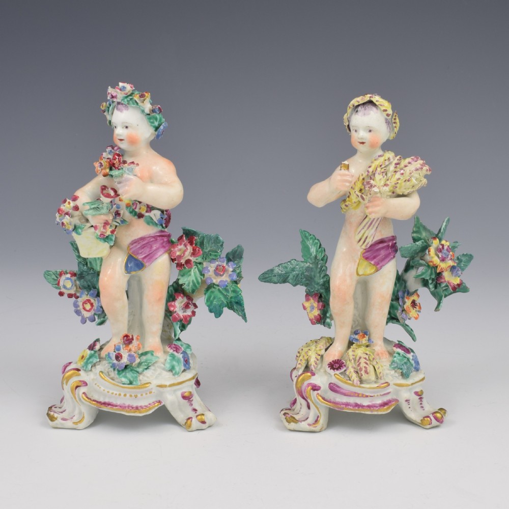 A set of four 18th-century Bow soft-paste porcelain figures representing the seasons, depicting putti on rococo scroll bases with colourful floral bocage. View II