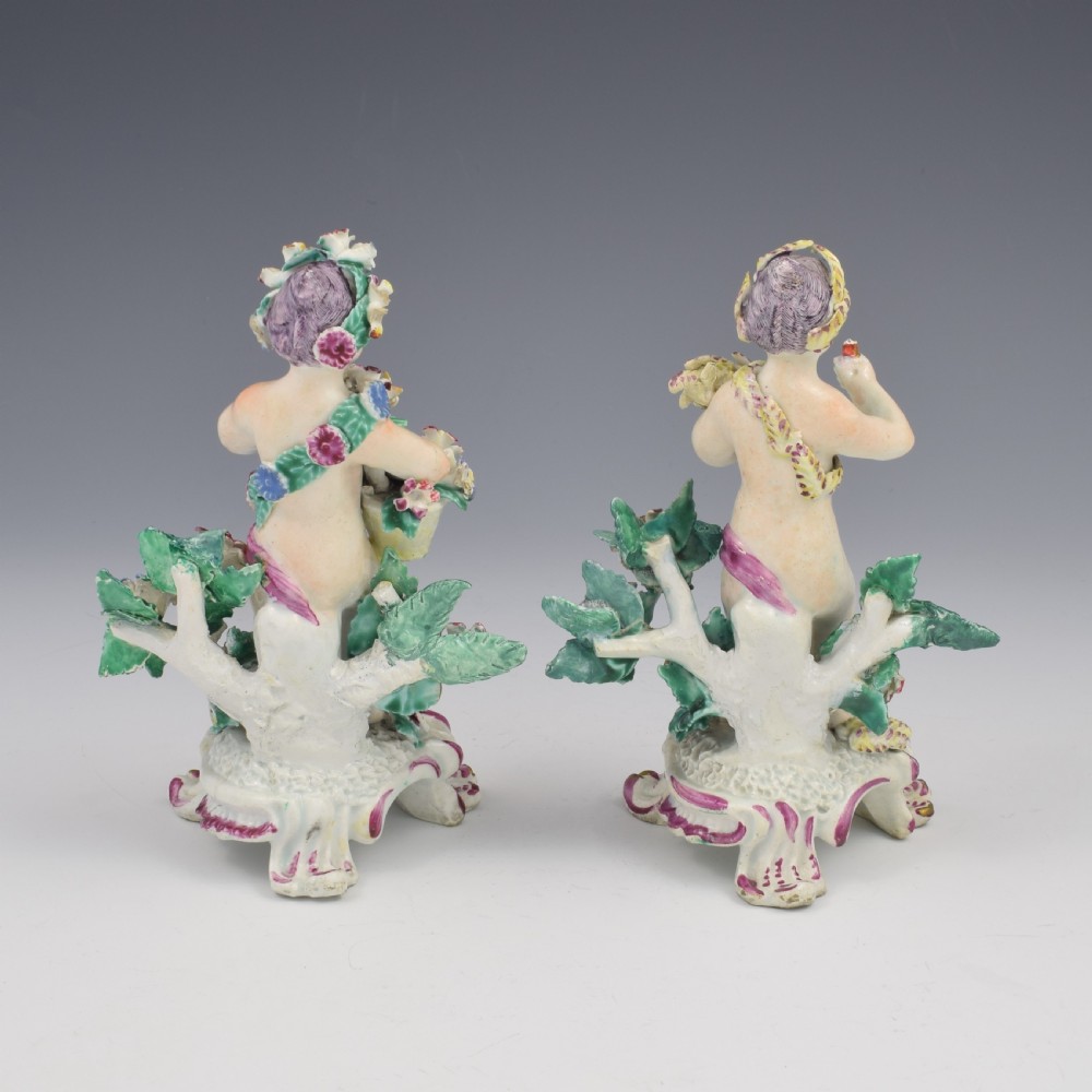 A set of four 18th-century Bow soft-paste porcelain figures representing the seasons, depicting putti on rococo scroll bases with colourful floral bocage. View IV