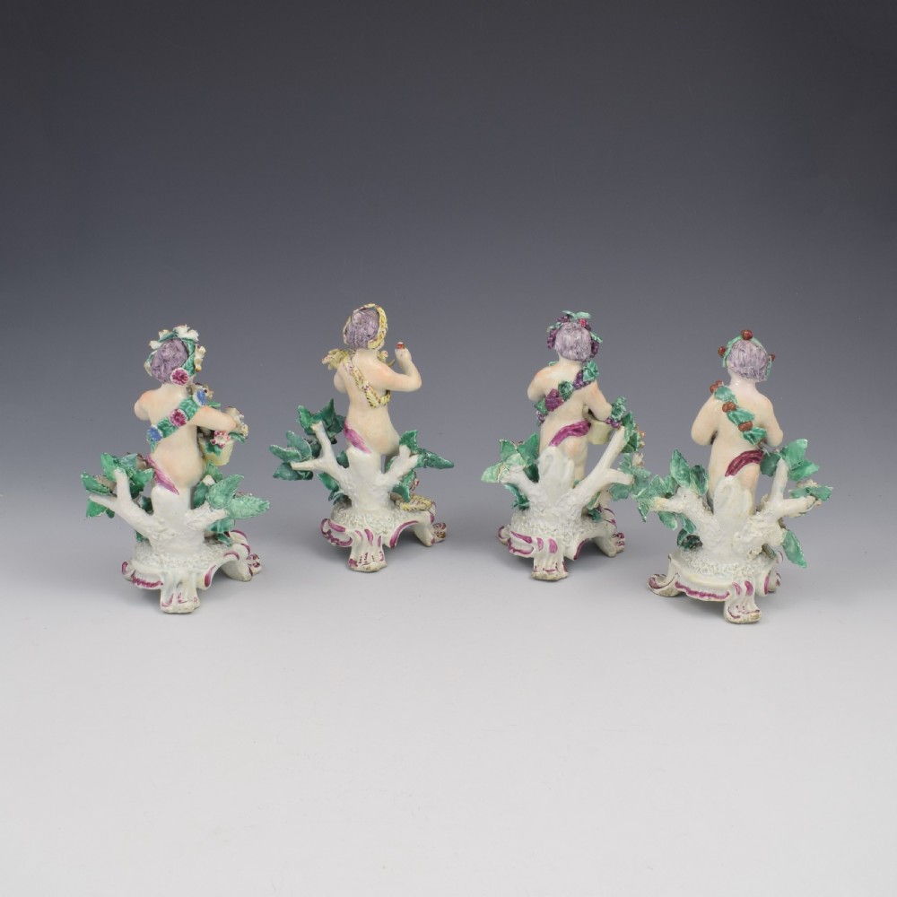 A set of four 18th-century Bow soft-paste porcelain figures representing the seasons, depicting putti on rococo scroll bases with colourful floral bocage. View X