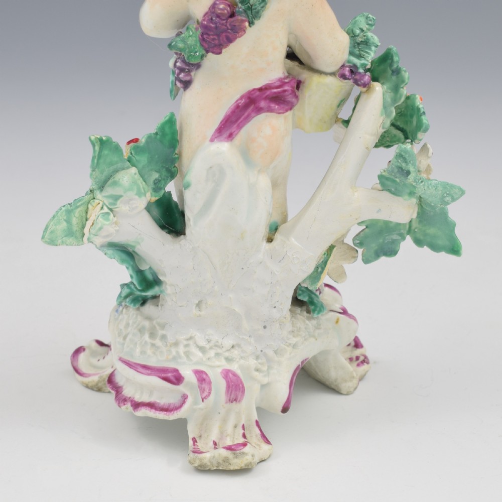 A set of four 18th-century Bow soft-paste porcelain figures representing the seasons, depicting putti on rococo scroll bases with colourful floral bocage. View XX