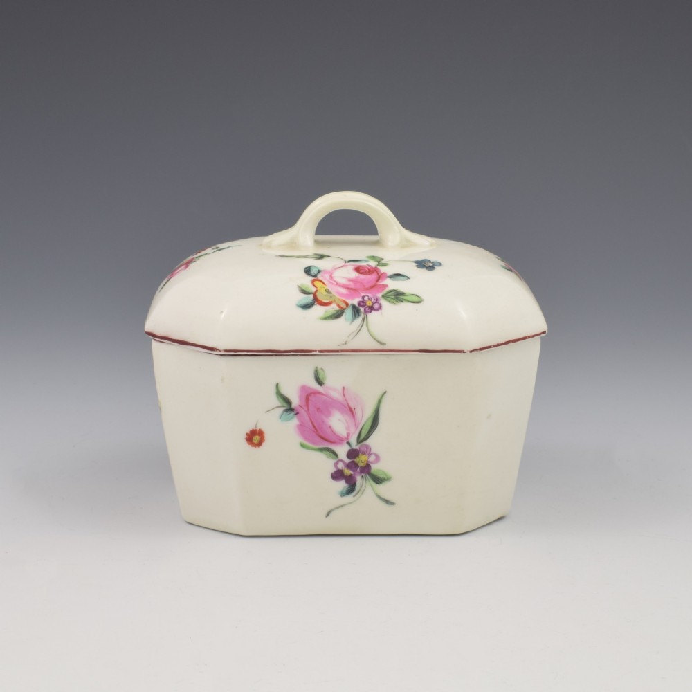 An 18th-century off-white porcelain butter tub with a fitted cover, top handle, and hand-painted floral motifs. View II